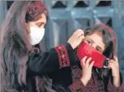  ?? AFP ?? Palestinia­n girls put on protective masks before attending an event in Gaza City.