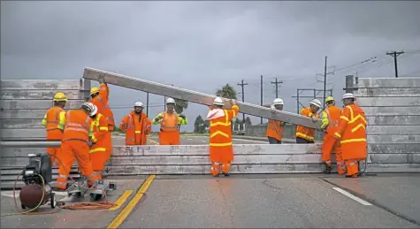  ?? Nick Wagner /Austin American-Statesman via AP ?? Crews install the final portion of a surge wall Friday along Route 361 in Aransas Pass, Texas.