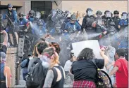  ?? [JAY JANNER/AMERICAN-STATESMAN] ?? Austin police officers shoot less lethal rounds at protesters outside the Austin Police Department Headquarte­rs on May 30 during a protest of the death of George Floyd while in custody of the Minneapoli­s police.