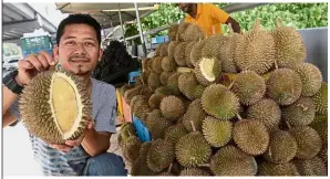  ??  ?? Good news: Aindinadha showing the durians sold at his roadside stall along Jalan Bayan Lepas in Penang.