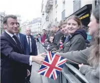  ?? — AFP ?? French President Emmanuel Macron shakes hands with onlookers gathered outside the Elysee Palace, in Paris.