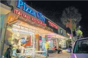  ?? JENNIFER LETT/SUN SENTINEL ?? Pizza City owner Dave Nardi, center, is seen outside his Fort Lauderdale restaurant, which offers CBD oil-infused pizzas and smoothies. Some CBD-laced foods contain trace amounts of THC.