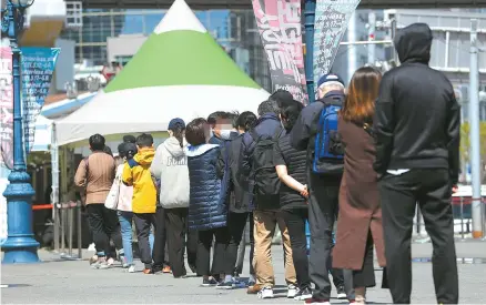 ?? Yonhap ?? People stand in line to get COVID-19 tests at a temporary testing center in front of Seoul Station, Wednesday, the day after Korea’s daily new coronaviru­s cases rose to 731, the largest number in 97 days.