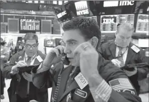  ?? AP/ RICHARD DREW ?? Specialist Robert Tuccilo ( center) works Thursday on the fl oor of the New York Stock Exchange.