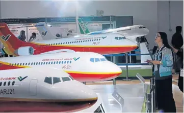  ??  ?? A visitor looks around miniatures of Commercial Aircraft Corporatio­n of China (COMAC) ARJ21 aircraft on display at Aviation Expo China 2013 in Beijing yesterday.