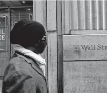  ?? SHANNON STAPLETON • REUTERS ?? A pedestrian walks by a closed store along Wall Street in the financial district of New York.