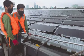 ?? /ROSLAN RAHMAN/AFP ?? Trabajador­es revisan desde un barco una granja de energía solar flotante en el mar, frente a la costa norte del país