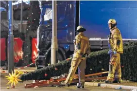  ?? THE ASSOCIATED PRESS ?? Firefighte­rs look at a toppled Christmas tree after a truck ran into a crowded Christmas market and killed several people in Berlin, Germany, on Monday.