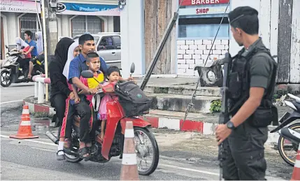  ?? HARAI WAEDAO ?? A security officer stands guard on a road in Narathiwat’s Muang district. The peace talks process has faced an uncertain fate as the government and a group representi­ng insurgents have failed to reach agreement on key issues.