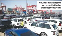  ??  ?? A WORKER inspects imported cars at a port in Qingdao, Shandong province, China.