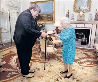  ?? Steve Parsons Getty Images ?? THE COMPOSER and conductor towers over Queen Elizabeth II as he receives the Queen’s Medal for Music at Buckingham Palace in London in 2016. He composed 50 works over the span of career.