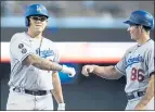  ?? ROSS D. FRANKLIN — THE ASSOCIATED PRESS ?? Dodgers pitcher Julio Urias, left, gets a fist-bump from first base coach Clayton McCullough after singling in the fourth inning.