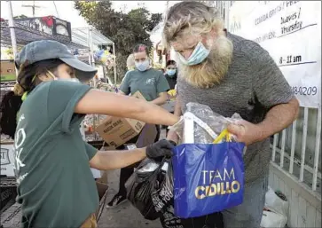  ?? Genaro Molina Los Angeles Times ?? VOLUNTEERS pass out personal protective equipment along with food in Los Angeles this fall. It has been months since the federal government provided f inancial help for Americans struggling during the pandemic.