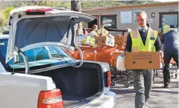  ?? ELIZABETH MARIE HIMCHAK U-T COMMUNITY PRESS ?? Volunteer Boden Quiner carries food to a vehicle at The Community Food Connection. Grocery stores donate food. Volunteers pick up the goods.