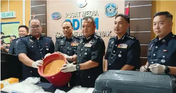  ?? ?? Mancha (third right) shows a pail containing the ecstasy mixture seized from the apartment. With him are Sarawak Deputy Police Commission­er Datuk Ibrahim Darus (fourth right) and Miri police chief ACP Alexson Naga Chabu (second right).