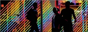  ??  ?? People walk past rainbow coloured lights outside a building in New York City. The city is preparing for the 50th anniversar­y of the Stonewall uprising. (AFP)