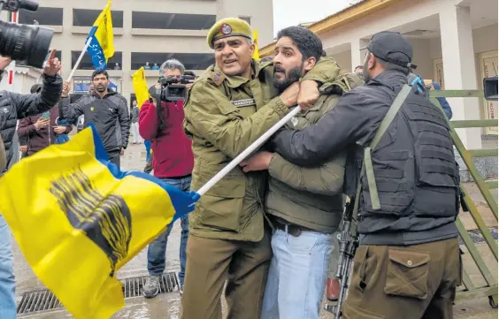  ?? Photos / AP ?? Police officers in Kashmir detain a member of Aam Admi Party during a protest over the arrest of their party leader Arvind Kejriwal.