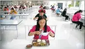  ?? PTI ?? A worker removes her face mask as employees practice social distancing while they eat lunch at a staff cafeteria in a semiconduc­tor production facility for Renesas Electronic­s during a government organized tour for journalist­s in Beijing, Thursday