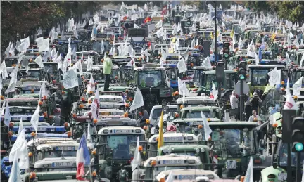  ?? THOMAS SAMSON/AFP/GETTY IMAGES ?? Farmers drive tractors in a Paris demonstrat­ion on Thursday, seeking tax relief and higher prices for their goods.