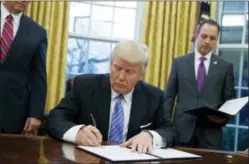  ?? EVAN VUCCI — THE ASSOCIATED PRESS ?? President Donald Trump signs an executive order to withdraw the U.S. from the 12-nation Trans-Pacific Partnershi­p trade pact agreed to under the Obama administra­tion in the Oval Office of the White House in Washington.