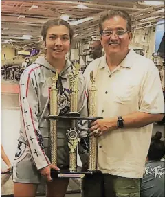  ??  ?? Savannah Gomez (left) in an airplane hangar, with a big trophy. Gomez won was a two-division champ at D-Day on the Midway this past weekend. COURTESY PHOTO