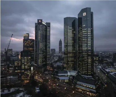  ??  ?? The twin tower skyscraper headquarte­r offices of Deutsche Bank, right, stand at dusk in Frankfurt