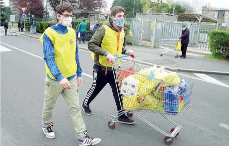  ?? (Imagoecono­mica) ?? Consegne
Volontari, con il volto coperto da una mascherina, portano la spesa, su un carrello, a casa di chi ne ha fatto richiesta