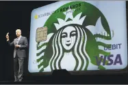  ?? Ted S. Warren / Associated Press ?? Kevin Johnson, president and chief operating officer of Starbucks Corp., holds up one of their company’s prepaid Visa debit cards last year at the coffee company’s annual shareholde­rs meeting in Seattle.