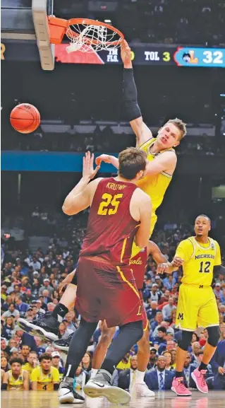  ?? THE ASSOCIATED PRESS ?? Michigan forward Moe Wagner dunks over Loyola-Chicago center Cameron Krutwig (25) during the second half of their semifinal Saturday night at the Final Four in San Antonio. Michigan won 69-57.