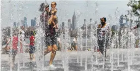  ?? AP PHOTO/EDUARDO MUNOZ ALVAREZ ?? People enjoy the day playing in a water fountain as the Empire State Building is seen from the Williamsbu­rg section of Brooklyn on Saturday in New York. Americans from Texas to Maine sweated out a steamy Saturday as a heat wave spurred cancelatio­ns of events from festivals to horse races and the nation’s biggest city ordered steps to save power to stave off potential problems.