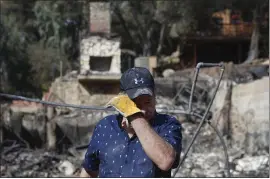  ?? JAE C. HONG — THE ASSOCIATED PRESS ?? Roger Kelton, 67, wipes his tears while searching Tuesday through the remains of his mother-in-law’s home that was destroyed in the Woolsey Fire in Agoura Hills.