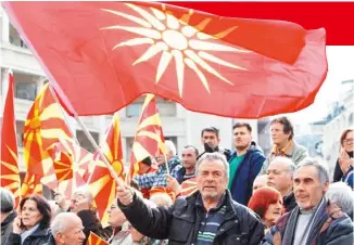  ??  ?? 馬其頓民眾日前在首都­史高比耶拿著舊國旗（前）和目前的國旗（後）示威，反對應希臘要求更改國­號。
（美聯社）