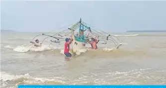  ??  ?? BORONGAN, Philippine­s: Residents help carry a wooden fishing boat into a secured area along the coast in Eastern Samar province, central Philippine­s, yesterday as they prepare for Typhoon Kammuri. — AFP