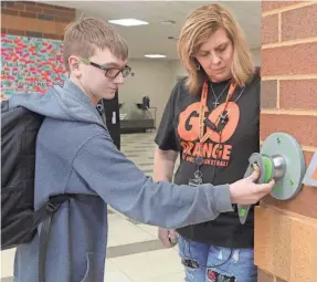  ?? PHIL MASTURZO/USA TODAY NETWORK ?? Keith Carlson, supervised by school safety team member Luan Haas, unlocks his cellphone from a sealed Yondr pouch at the end of classes at Ellet Community Learning Center in Akron, Ohio.