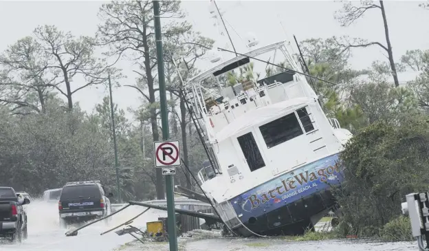  ??  ?? 0 A boat is washed up near a road after Hurricane Sally moved through the area in Orange Beach, Alabama