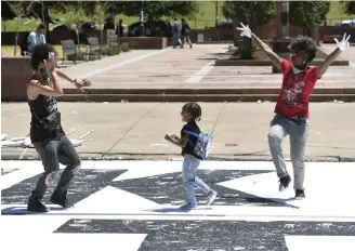  ?? Andy Cross, The Denver Post ?? Black Lives Matter mural designer Adri Norris, right, along with good friend Bianca Mikahn and Mikahn’s child, Phoenix, 4, dance on the completed work Friday on Broadway between Colfax and 14th avenues.