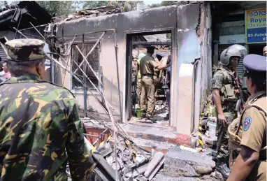  ?? PICTURES: REUTERS ?? DAMAGE: Sri Lanka’s Special Task Force and police officers stand guard near a burnt house after a clash between two communitie­s in Digana in the central district of Kandy yesterday.