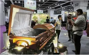  ?? — AP ?? Eco-friendly resting place: Visitors viewing a paper casket at the Asia Funeral and Cemetery Expo and Conference in Hong Kong.