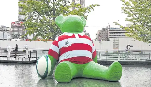  ??  ?? LEFT
A giant teddy bear wearing a replica Japan rugby shirt is seen in Osaka as it rains.