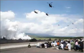  ?? TOMOHIRO OHSUMI/THE NEW YORK TIMES ?? Helicopter­s fly over spectators watching tanks firing smoke rounds during live-fire drills by Japan’s Self-Defense Forces in the foothills of Mount Fuji, where an audience of more than 26,000 attended, in Gotemba, on Sunday.