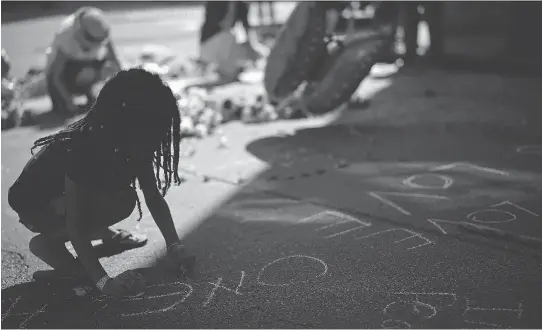  ?? WIN MCNAMEE/GETTY IMAGES ?? Seven-year-old Nyla-Fae Fox writes Love Wins in chalk at a makeshift memorial for Heather Heyer, who was killed during last weekend’s violence in Charlottes­ville.