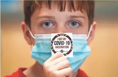  ?? ROB SCHUMACHER/THE REPUBLIC ?? Nine-year-old Logan Hute shows off his sticker after receiving his COVID-19 vaccine at Native Health Central clinic on Friday in Phoenix.