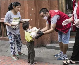  ?? RODRIGO ABD AP ?? Maria Isabel Nieto and her son, Jesus Anderson, receive their lunch on Thursday, provided to the homeless by a charity organizati­on in Lima, Peru, on the second week of a government decreed state of emergency that restricts residents to their homes.