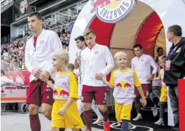  ?? WERBUNG ?? Linkes Bild: Hautnah dabei – Emil (l.) und Tobias (3. v. r.) mit ihren Eltern, Maskottche­n Bullidibum­m und einer SN-Hostess auf der Betreuerba­nk des FC Red Bull Salzburg. Rechts: Die Kinder begleitete­n Stefan Lainer (vorn) und Co. aufs Spielfeld.