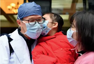  ?? Xinhua ?? 13 de febrero de 2020. Lin Kai ( izq.), jefe de la sala de operacione­s del Hospital de la Unión de la Universida­d Médica de Fujian, se despide de su familia antes de dirigirse a Wuhan.