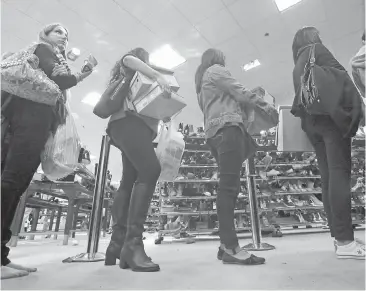  ??  ?? Shoppers line up with their purchases at a U.S. department store. Standing behind shoppers carrying small amounts of goods might not be the fastest way to get through the checkout.