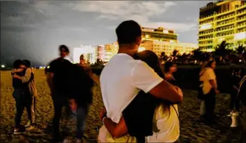  ?? Maria Alejandra Cardona / New York Times ?? People gather on a beach Monday for a vigil for the victims of the partially collapsed Champlain Towers South condo building in Surfside, Fla.