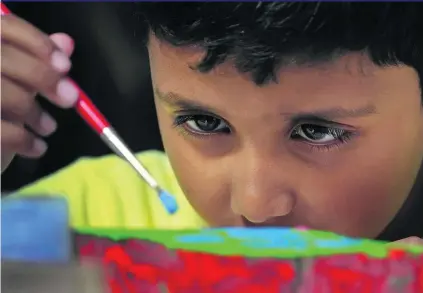  ?? Delores Johnson / The National ?? Elvin Mathew, 6, focuses on his painting yesterday at the Picture This art workshop for children with autism at Umm Al Emarat Park in Abu Dhabi. They and other children created their masterpiec­es, which will be on show at the park.