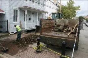  ?? AP PHOTO — BRIAN WITTE ?? Norman Sharps, a heavy equipment operator for the city of Annapolis, Md., rakes up debris that has washed into Maryland waters on Wednesday near the City Dock after last week’s record rainfall.