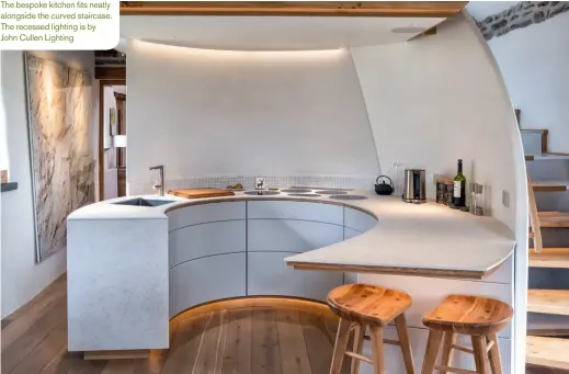  ??  ?? The bespoke kitchen fits neatly alongside the curved staircase. The recessed lighting is by John Cullen Lighting